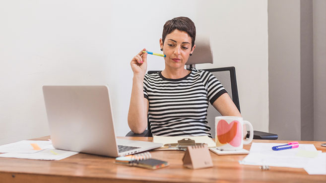 Mujer con un lápiz en la mano mientras estudia virtualmente desde su laptop