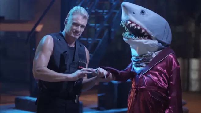 Dolph Lundgren recibiendo llaves de parte de un tiburón vestido de pijama