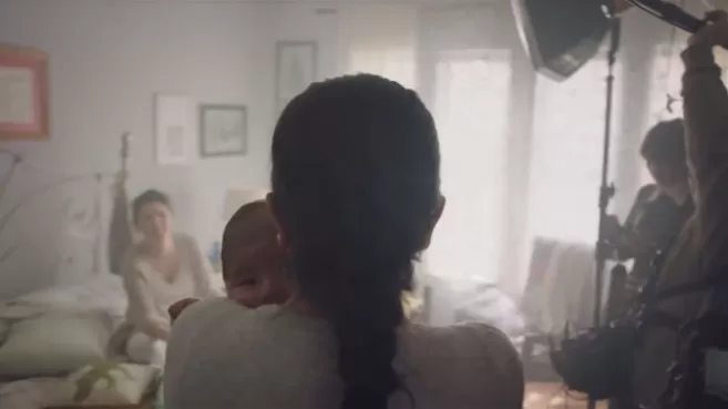 Madre cargando a su bebé detrás de cámaras de un comercial