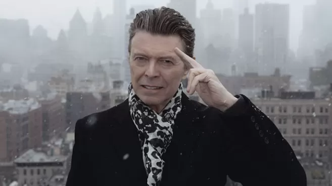 David Bowie vestido de negro y con bufanda saludando