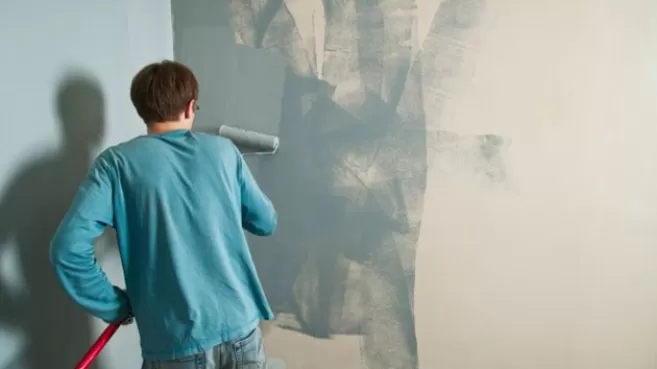 Hombre pintando la pared de su casa