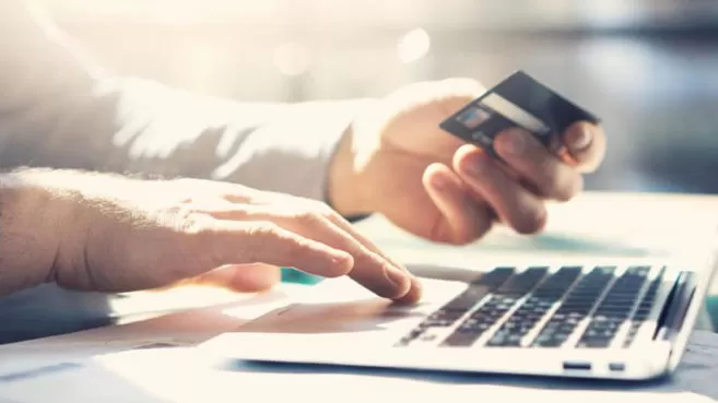 Manos con tarjeta de crédito y un portátil, haciendo una compra en línea