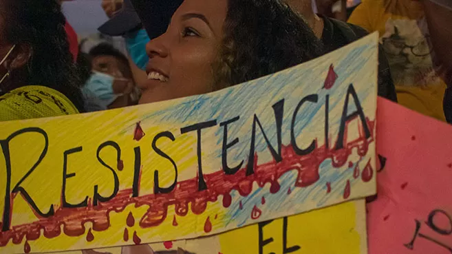Mujer jóven en marcha pacífica de Cartagena sostiene una pancarta que dice "Resistencia"