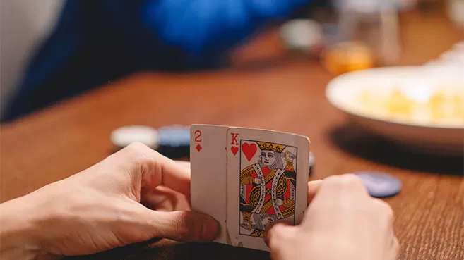 Manos sosteniendo dos cartas en un juego de poker