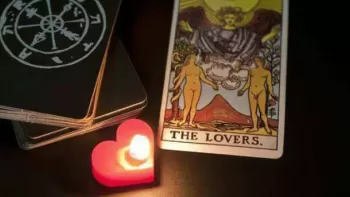 Cartas del Tarot junto a una vela roja, encendida, en forma de corazón
