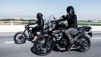 Norman Reedus con casco negro saludando mientras conduce su motocicleta acompañado de otro motociclista