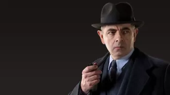 Rowan Atkinson con sombrero y con una pipa en la mano, interpretando al inspector Maigret