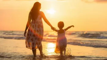 Madre con su hija caminando por la playa