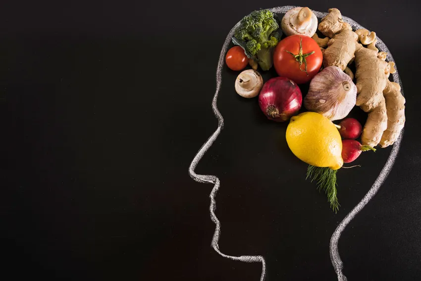 Cabeza dibujada con tiza sobre un tablero, con alimentos saludables como cerebro