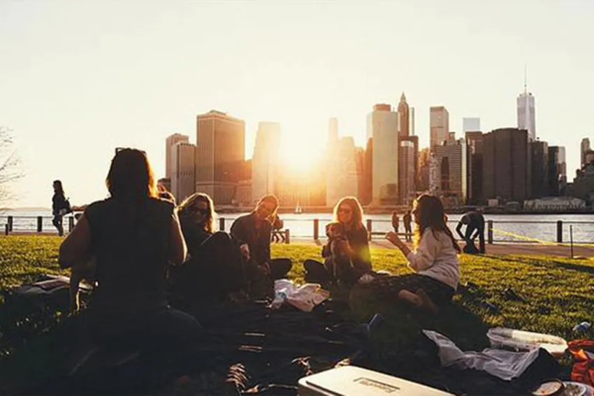 Cinco personas sentadas en la grama con vista a edificios de la ciudad