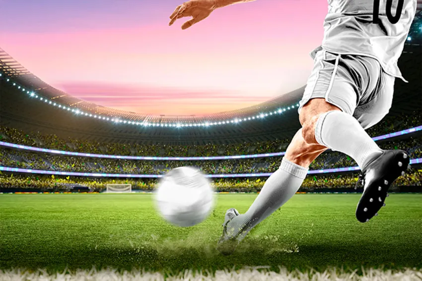 Apuestas de fútbol - Jugador de fútbol pateando un balón en el estadio