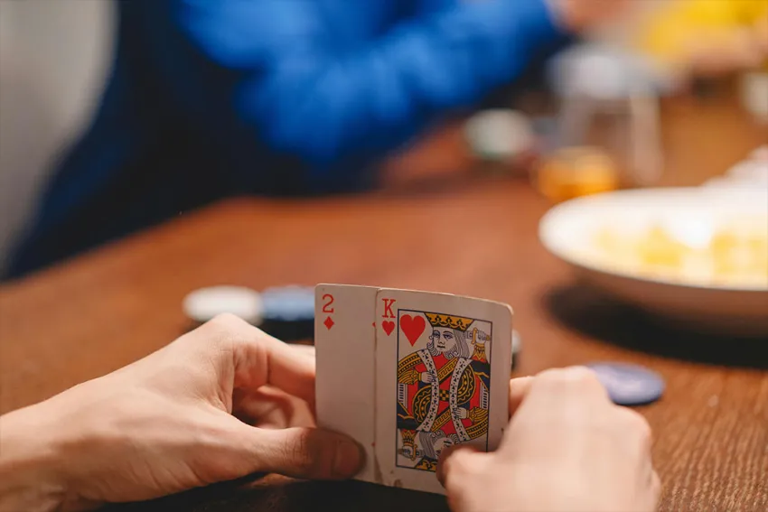 Manos sosteniendo dos cartas en un juego de poker