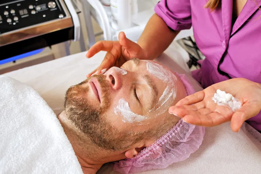 Cosmetóloga hace tratamiento estético facial a hombre