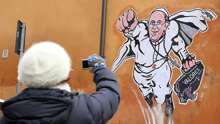 Persona fotografiando graffiti del Papa Francisco