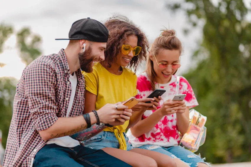 Grupo de jóvenes sonrientes usando sus celulares