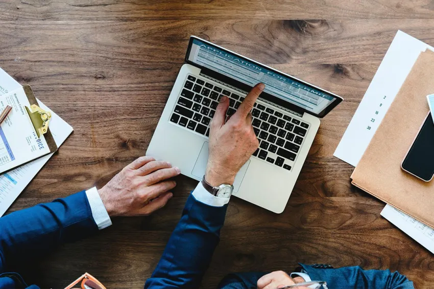 Manos en un escritorio con laptop y otros elementos de oficina