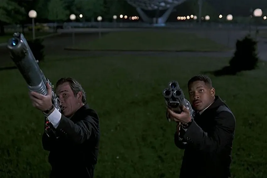 Tommy Lee Jones y Will Smith apuntando sus armas en una escena de Hombres de Negro (Men in Black)