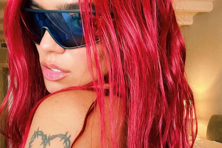 Primer plano de Karol G con gafas oscuras y el pelo rojo
