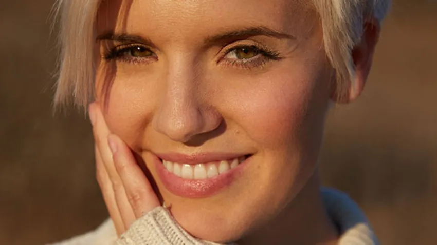 Maggie Grace en primer plano sonriendo y tocándose la cara