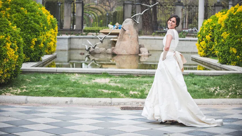 Mujer con vestido de novia blanco, delante de una fuente de agua