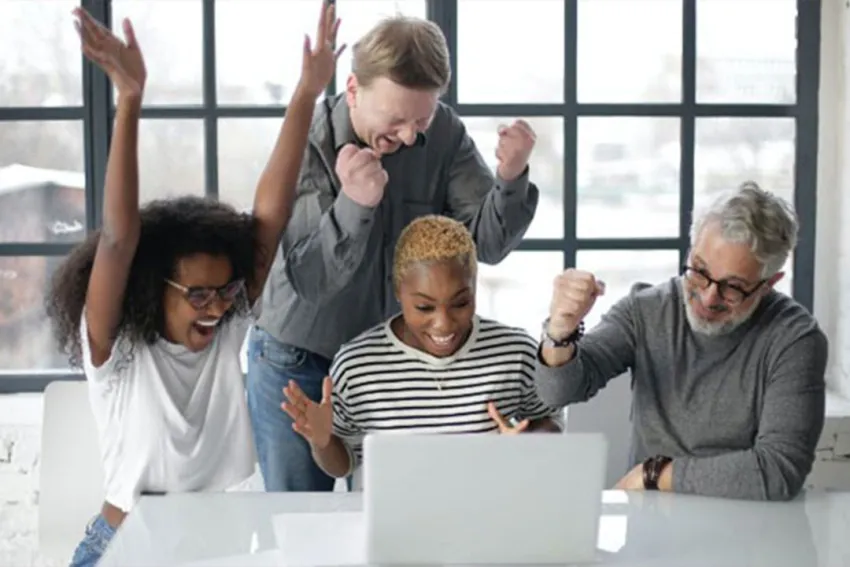 Grupo de personas celebrando frente a una laptop