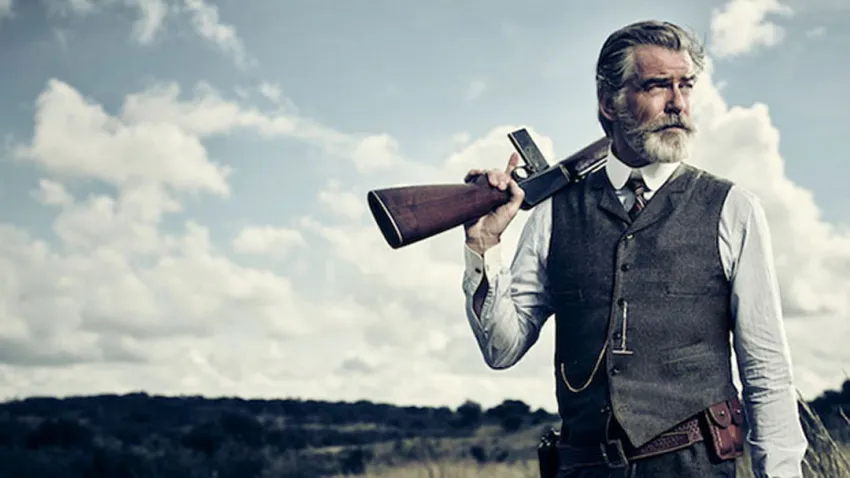 Pierce Brosnan como Eli McCullough sosteniendo una escopeta en el hombro, en la serie "The Son"