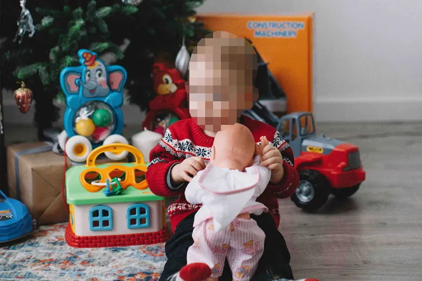 Niño recibiendo regalos debajo del árbol de Navidad