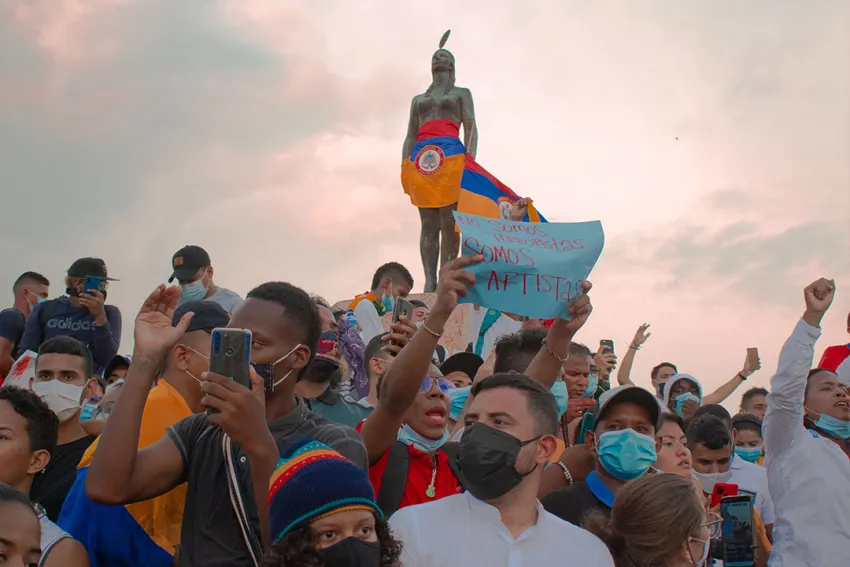 India Catalina vestida con la bandera de Colombia al revés, rodeada de manifestantes pacíficos