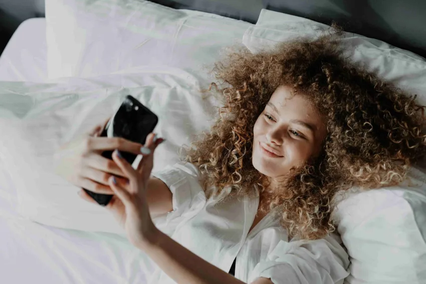 Mujer haciéndose una selfie en la cama