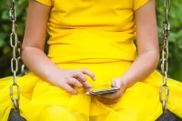 Niña usando un smartphone sentada en un columpio