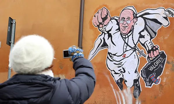 Persona fotografiando graffiti del Papa Francisco