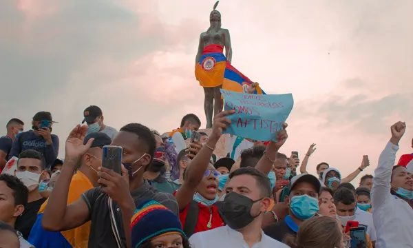 India Catalina vestida con la bandera de Colombia al revés, rodeada de manifestantes pacíficos