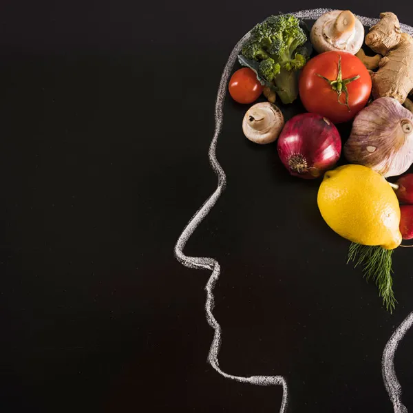 Cabeza dibujada con tiza sobre un tablero, con alimentos saludables como cerebro