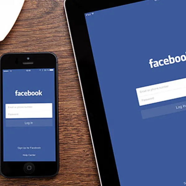 App de Facebook en un iPhone y un iPad que están sobre un escritorio
