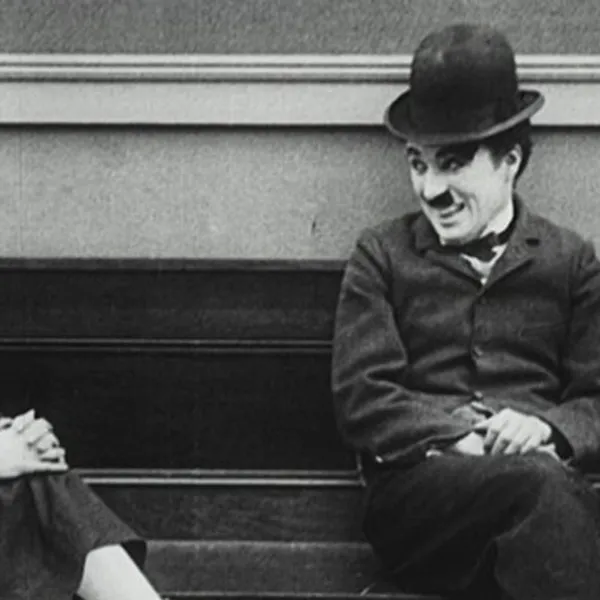 Charles Chaplin sentado en una banca sonriéndole a una mujer
