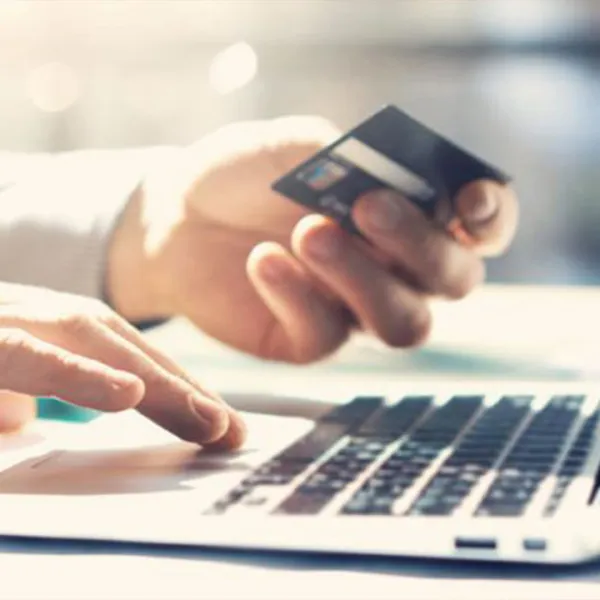 Manos con tarjeta de crédito y un portátil, haciendo una compra en línea