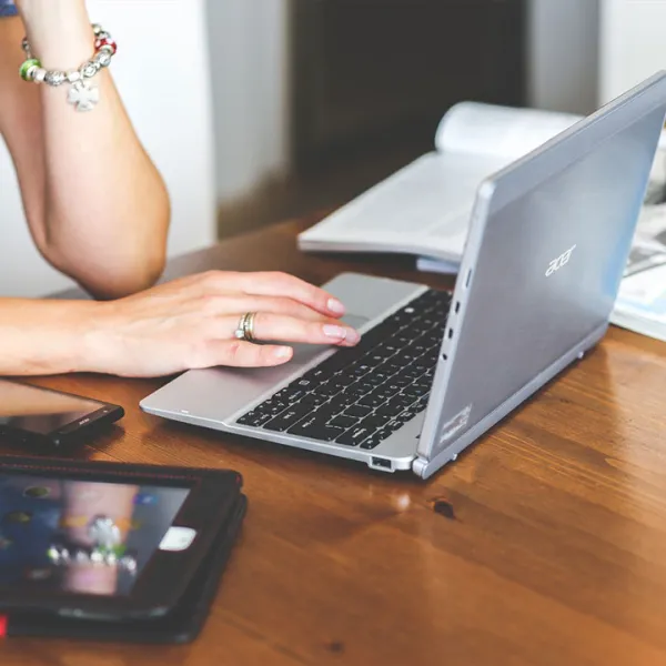 Manos de una mujer estudiando virtualmente desde su computador portátil