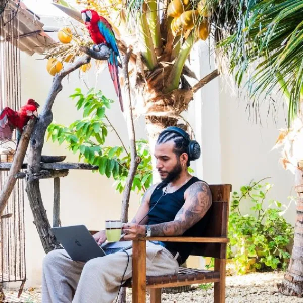Gangsta sentado en un patio junto a dos guacamayas