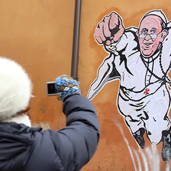 Persona fotografiando graffiti del Papa Francisco