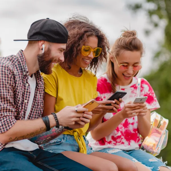 Grupo de jóvenes sonrientes usando sus celulares