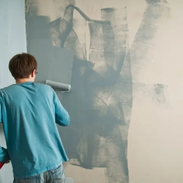 Hombre pintando la pared de su casa