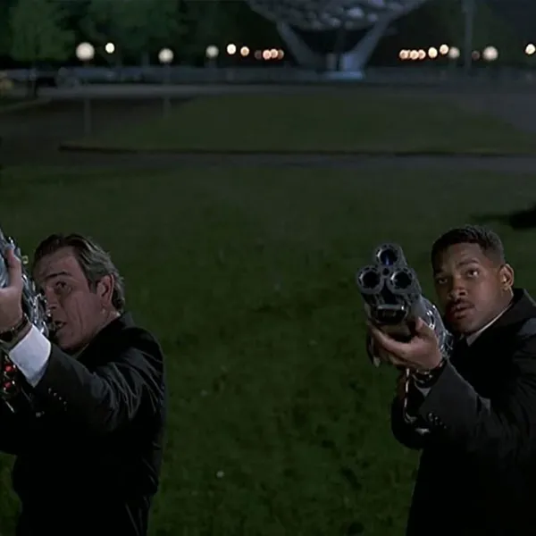 Tommy Lee Jones y Will Smith apuntando sus armas en una escena de Hombres de Negro (Men in Black)