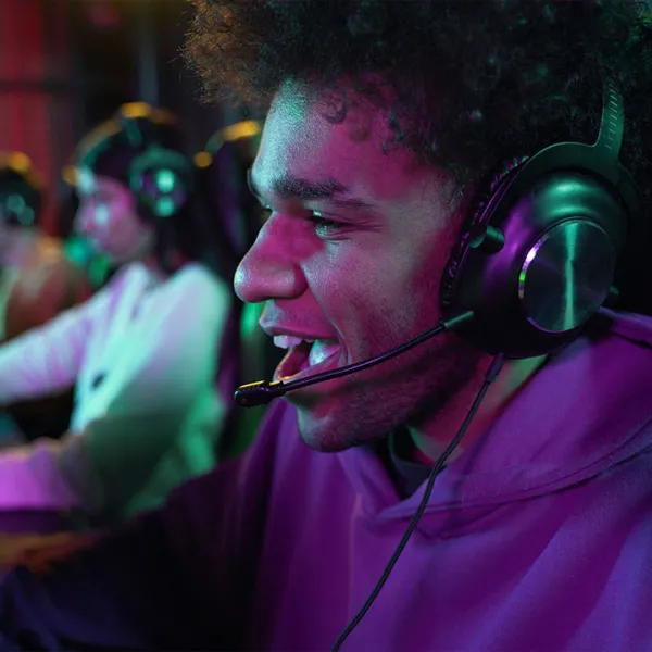 Joven sonriente con audifonos, jugando videojuegos