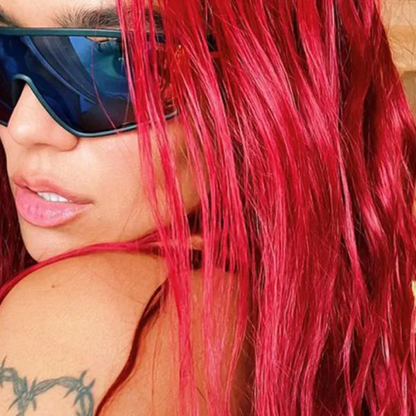 Primer plano de Karol G con gafas oscuras y el pelo rojo