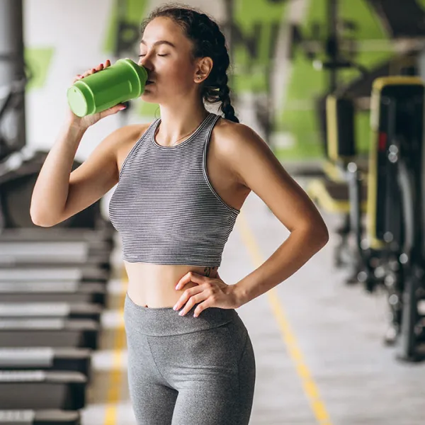 Mujer tomando proteina en el gimnasio