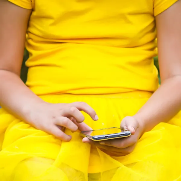 Niña usando un smartphone sentada en un columpio