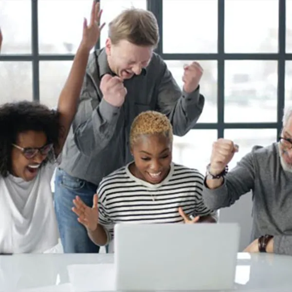 Grupo de personas celebrando frente a una laptop