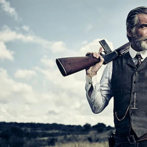 Pierce Brosnan como Eli McCullough sosteniendo una escopeta en el hombro, en la serie "The Son"