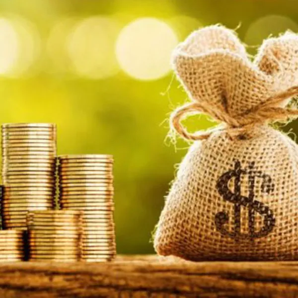 Pila de monedas al lado de un saco de dinero