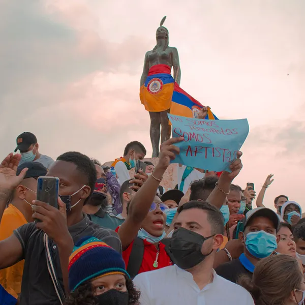 India Catalina vestida con la bandera de Colombia al revés, rodeada de manifestantes pacíficos